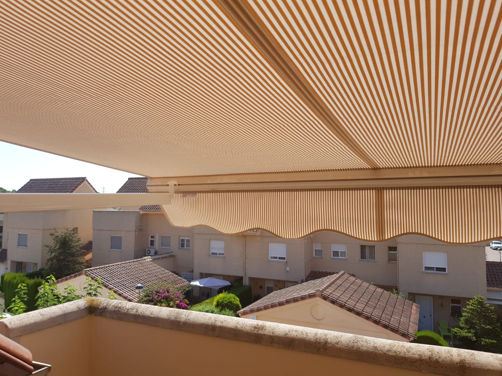 Toldo de brazo extensible de color amarillo en una terraza con mira hacia afuera.
