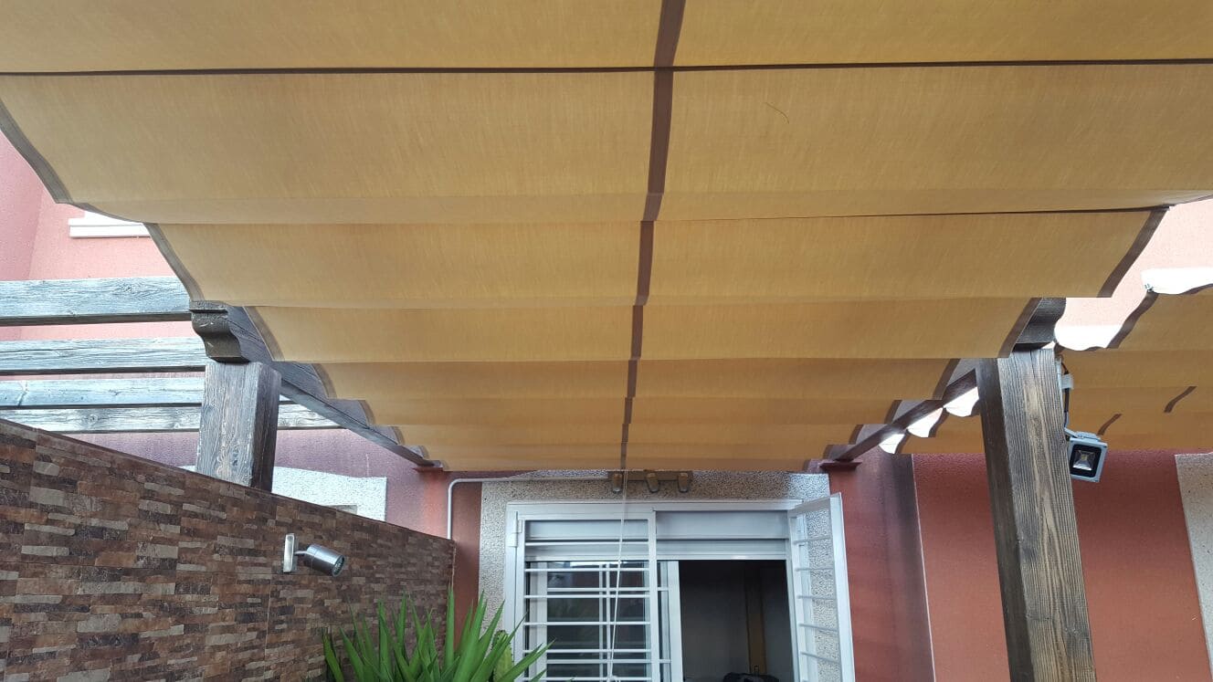 Toldo patio tipo andaluz entre paredes de color blanco con motorización