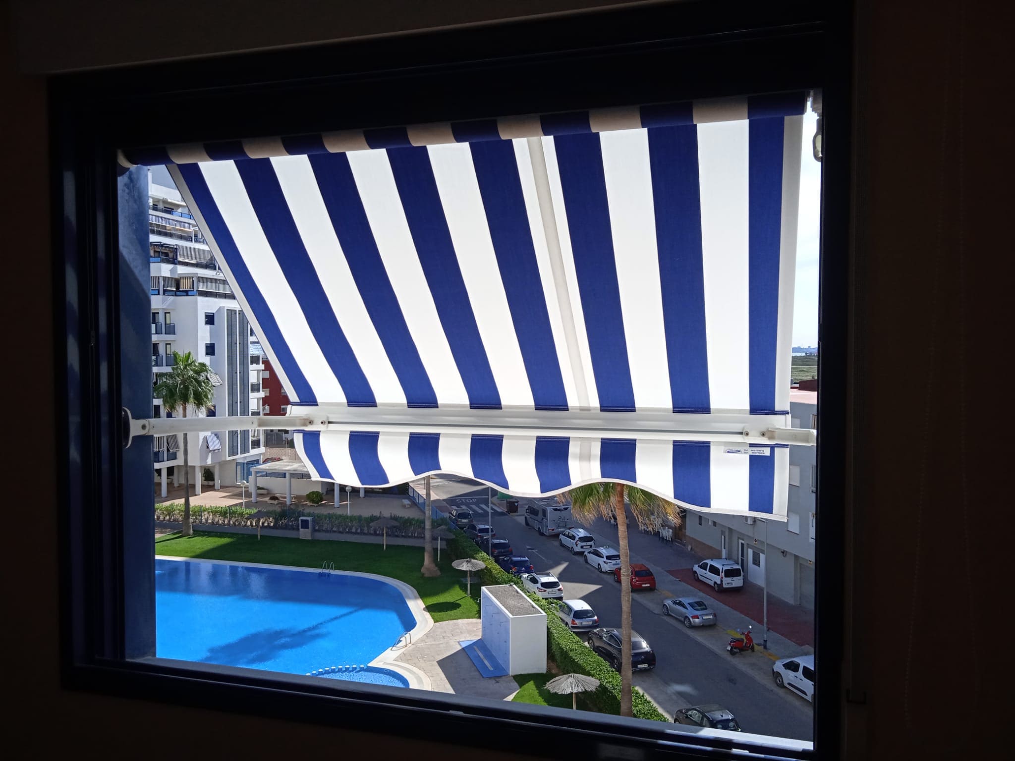 Estor blanco punto recto con franjas azules con mirado a ciudad y piscina